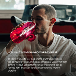 Athlete drinking electrolytes from a red 'Puresport' bottle in a gym setting