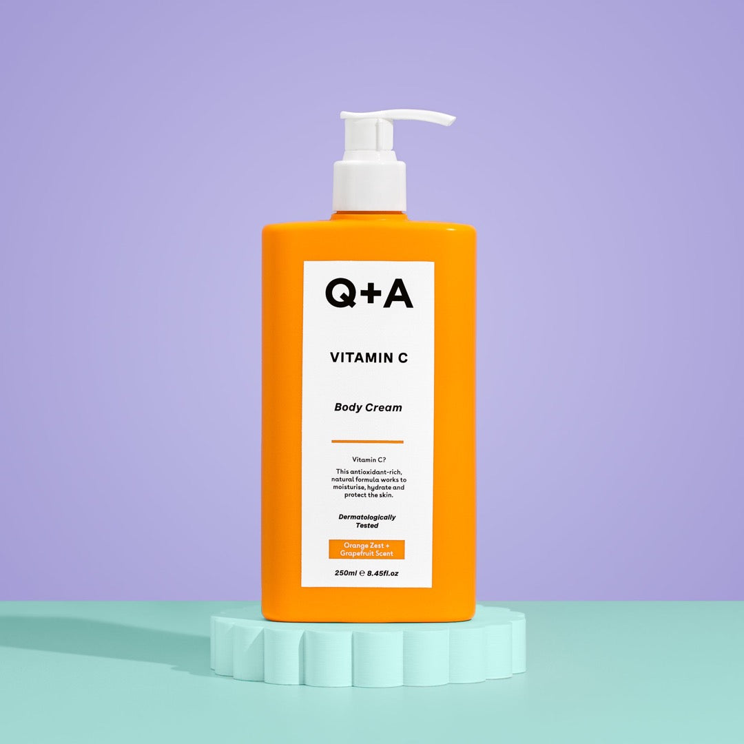 Q+A Vitamin C Body Cream bottle sat on a blue tile