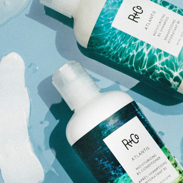 a close up of two R+Co Atlantis Moisturizing B5 Conditioner bottles