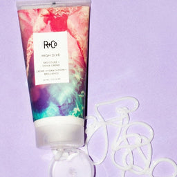 a tube of R+Co High Dive Moisture + Shine Crème with its contents being squeezed out