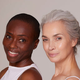 Two women with different skin tones standing side by side against a neutral background