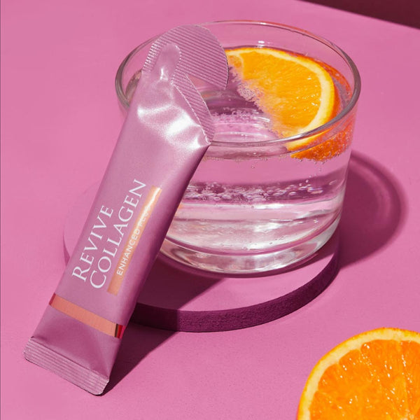 a single Revive Collagen Enhanced serving leant against a cup with a slice of orange inside