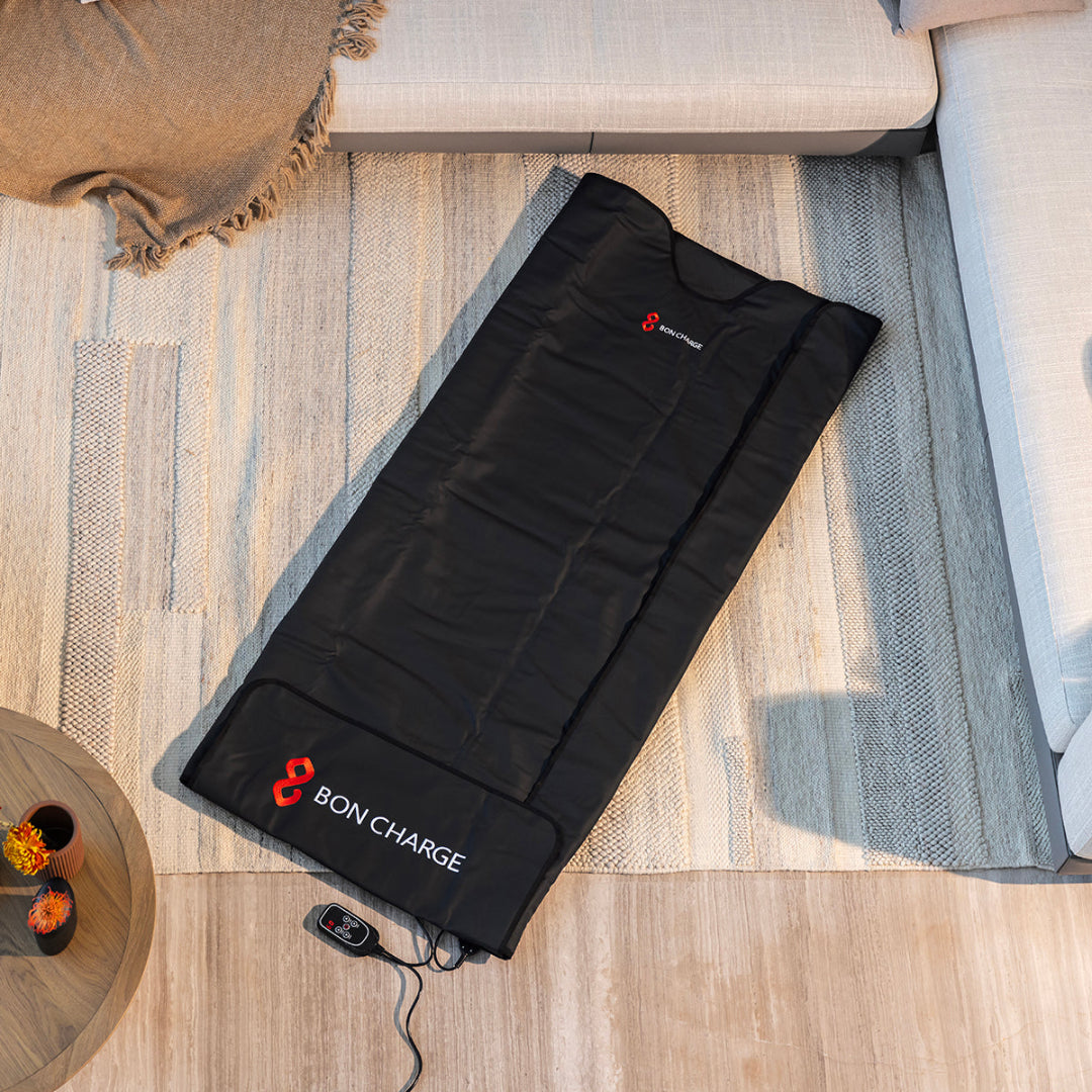 Black heating pad with 'BON CHARGE' branding on a wooden floor.