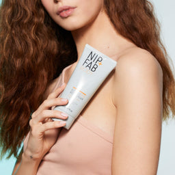 a model holding a tube of cream to her shoulder