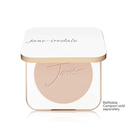 A Jane Iredale makeup compact with a white lid and a clear base showing a round blush or pressed powder in a light peach-beige shade. The compact has a thin metallic gold frame.