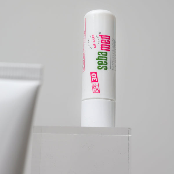 White lip balm with pink text on a gray background