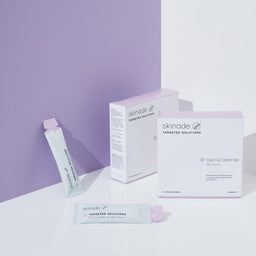 two packets of Skinade Targeted Solutions Derma Defense A and D Boost in front of a purple wall