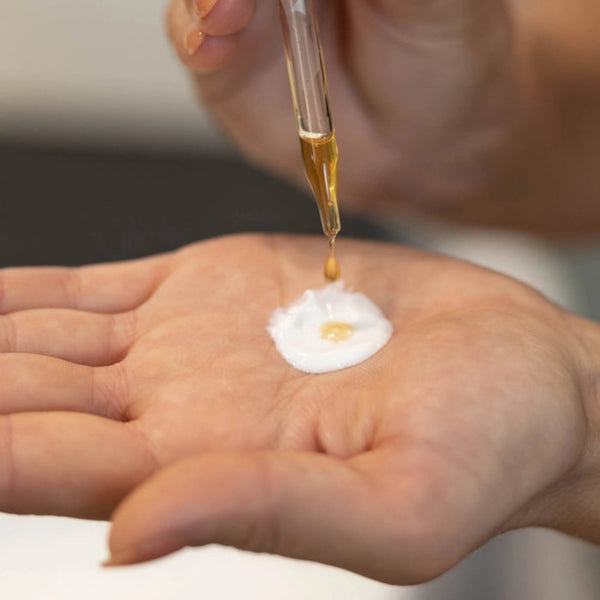 a hand applying the tanning drops to their hand with a pipette