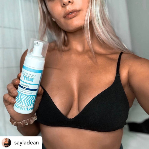 a woman holding a bottle of Skinny Tan Self-Tanning Mousse Medium close to her chest