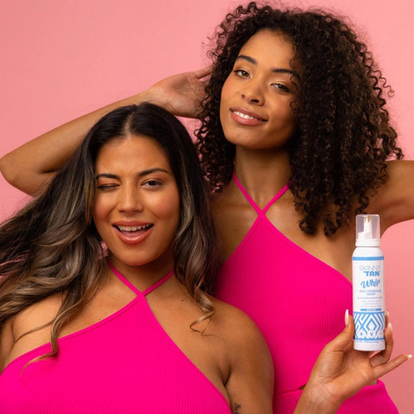 two women holding a bottle of Skinny Tan Self-Tanning Whip Medium to the camera