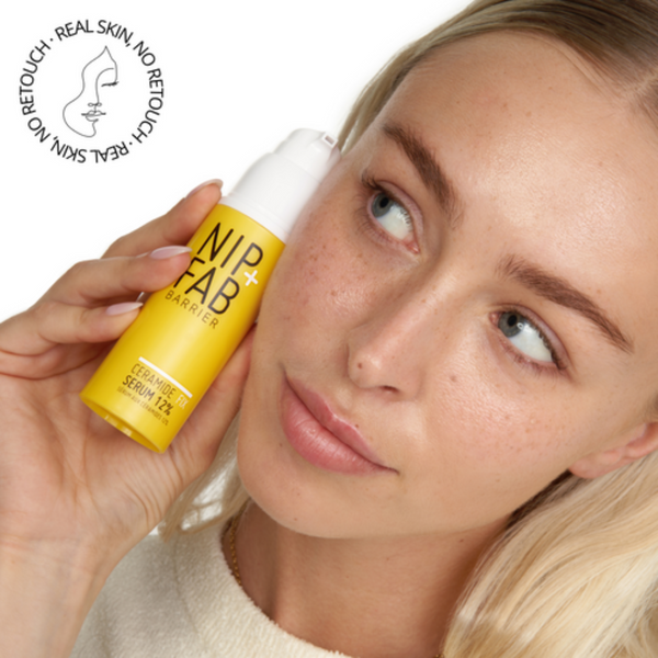 A model holding the serum up to her face