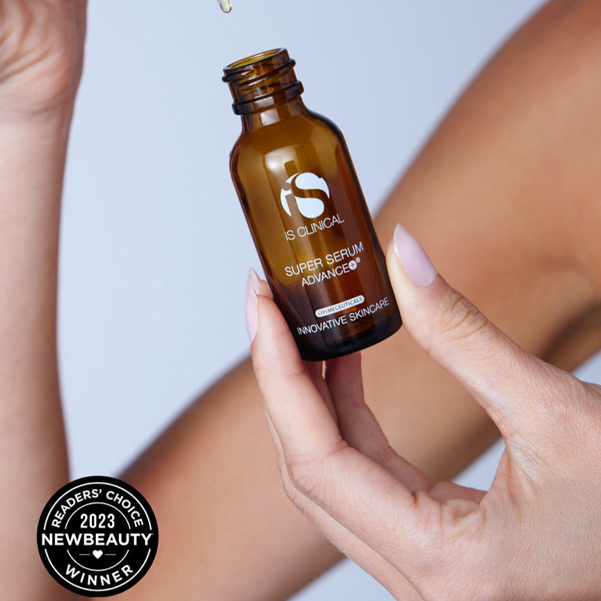 Brown serum bottle with dropper held by a hand, against a neutral background.