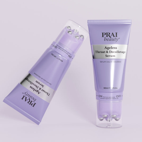 Two lavender tubes of PRAI beauty Ageless Throat & Decolletage Serum, one standing upright and the other tilted on its side, on a light lavender background.