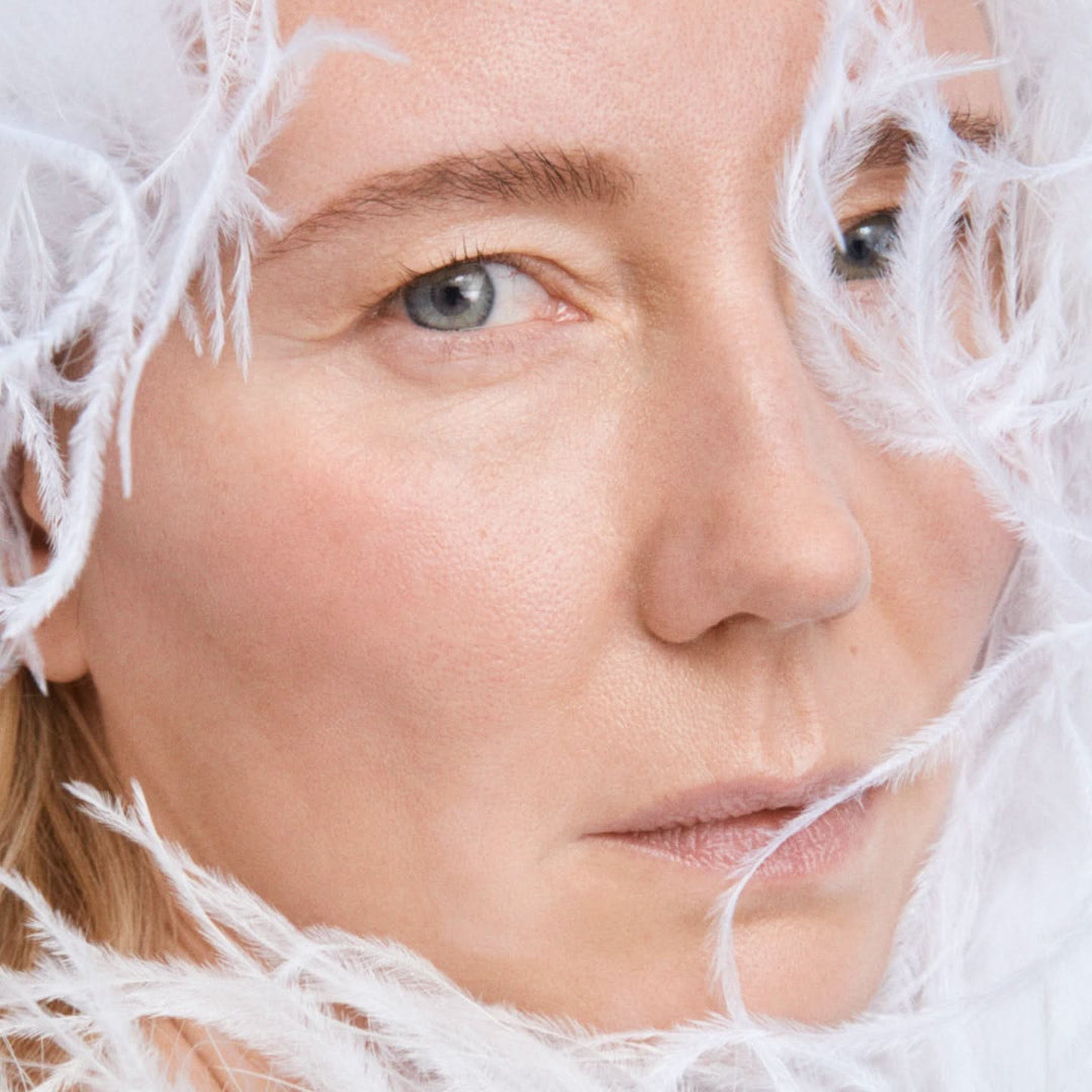 Close-up of a person's face with frosty white strands around, possibly indicating cold weather or a winter theme.