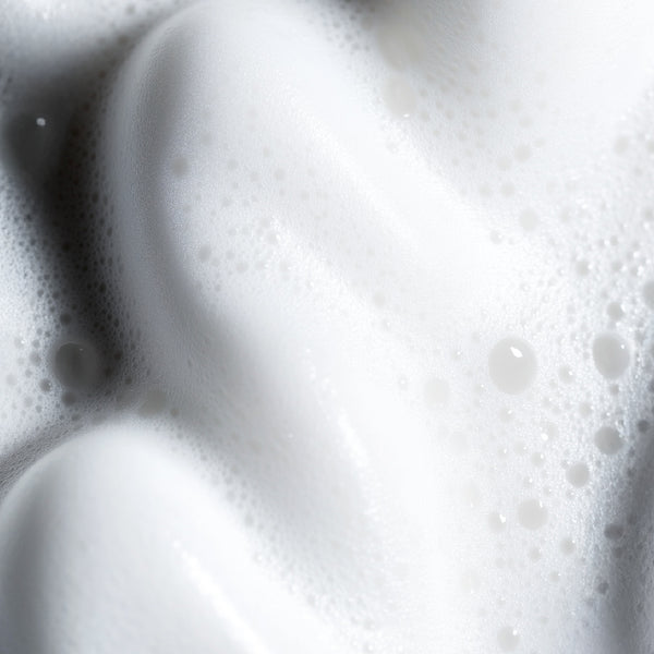 Close-up of thick, white lather or foam with fine bubbles and soft shadows.