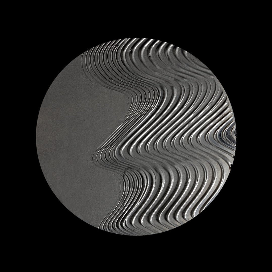 A circular gray object with a wavy, layered ribbed pattern on a solid black background.