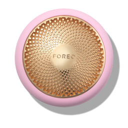 A FOREO facial cleansing brush head in a top-down view, featuring a light pink silicone outer ring and a metallic gold inner bristle pad with the FOREO logo in the center.