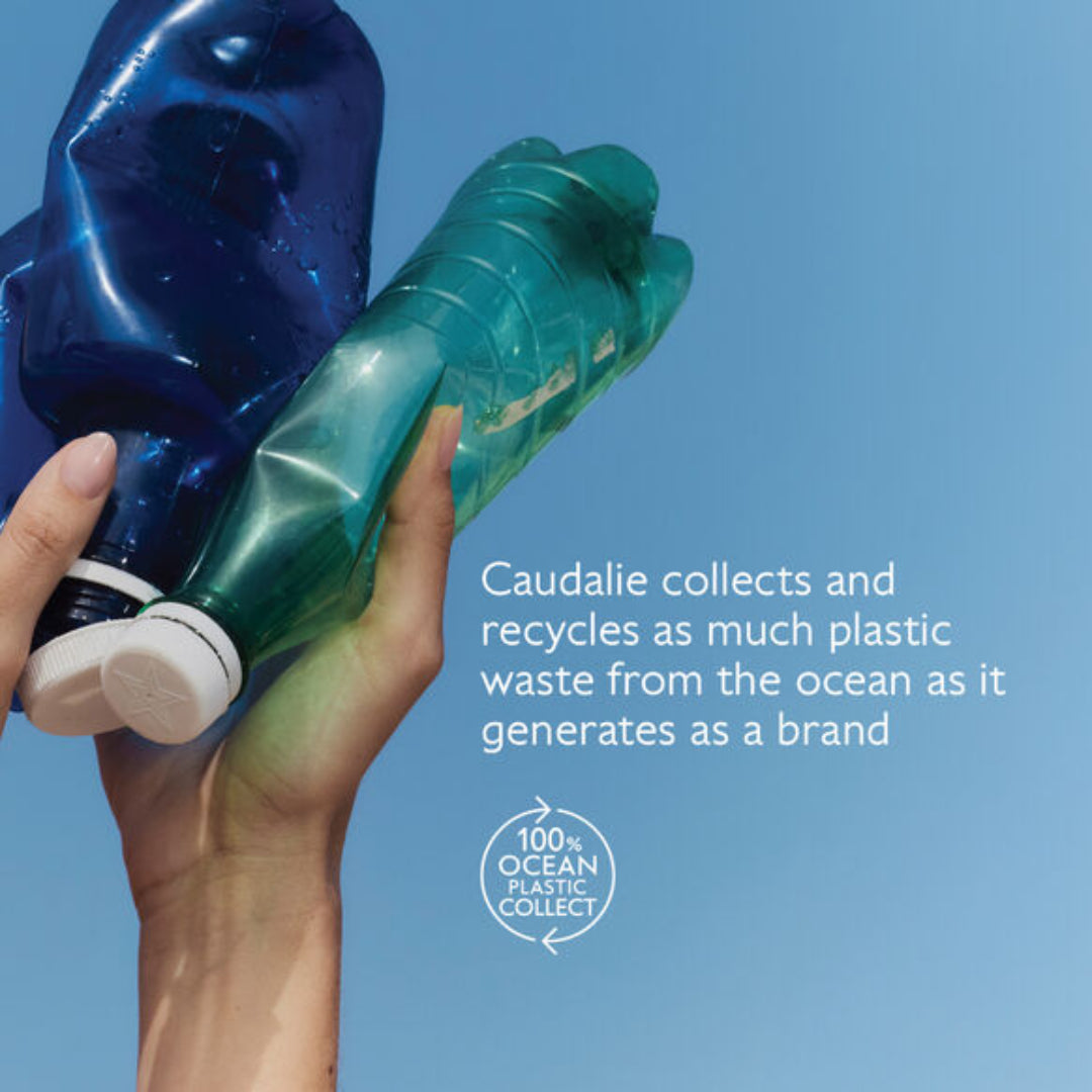 Hand holding two plastic bottles with text about Caudalie's ocean plastic collection on a blue background