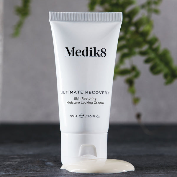 Medik8 Ultimate Recovery tube upright on top of a drop of texture