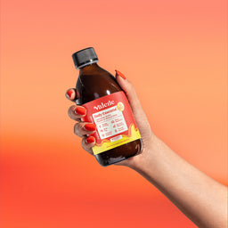 Hand holding a bottle of Valerite syrup against an orange gradient background