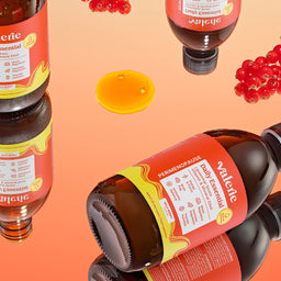 Bottles of Valenol with red berries and honey on an orange background