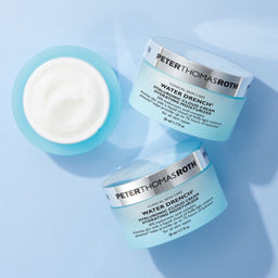 a birds eye view of three tubs of Peter Thomas Roth Water Drench Hyaluronic Cloud Cream Hydrating Moisturizer with one tubs lid removed