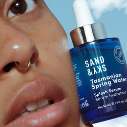 Model holding Sand & Sky Tasmanian Spring Water Splash Serum against her face
