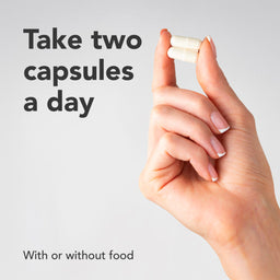 Hand holding two capsules with text on a light gray background