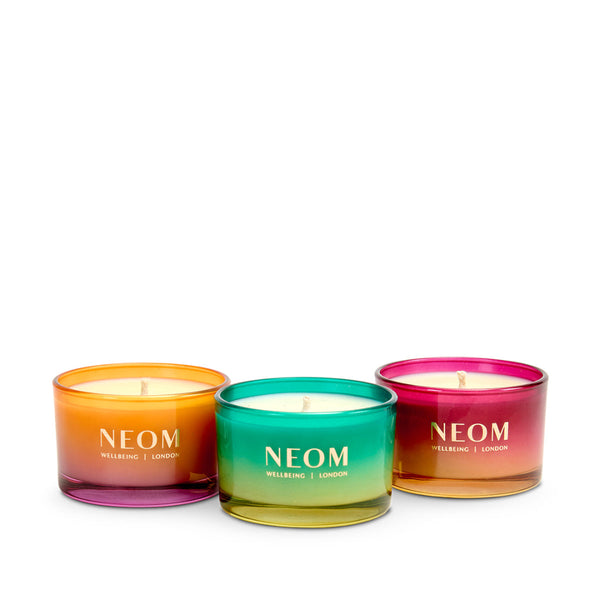 Three NEOM candles with gradient colors on a white background