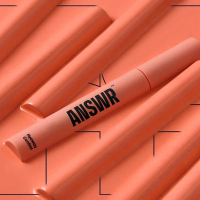 Orange makeup products with 'ANSWR' branding on a matching background