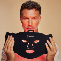 Man Holding Red Light Face Mask Towards Face