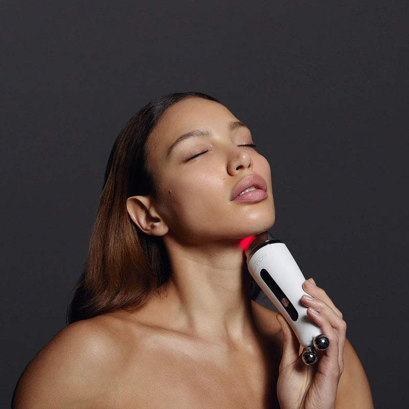 Woman using a handheld device on her neck against a dark background