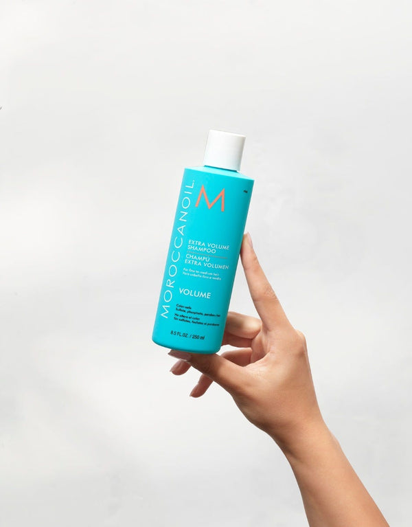 Moroccanoil Extra Volume Shampoo being held to the air