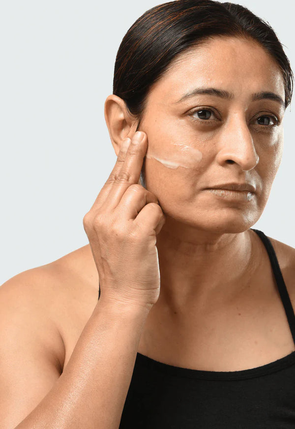 a women applying Minimalist Granactive Retinoid 02% to her cheek