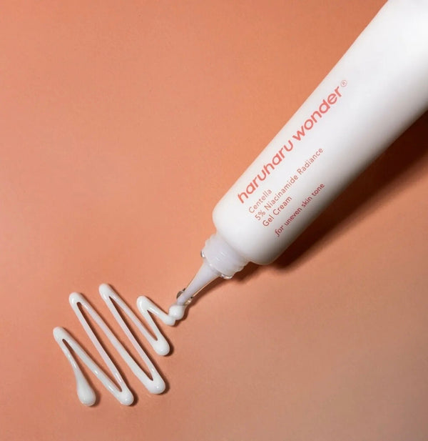 Haruharu wonder cream bottle with white cream being dispensed on a peach background