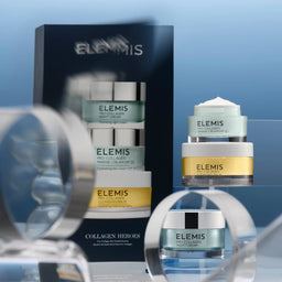Elemis skincare products on a reflective surface with a blue gradient background