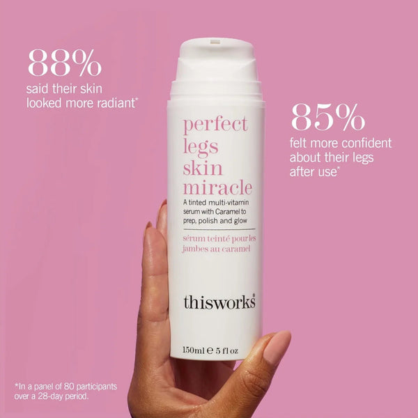 Hand holding a bottle of 'thisworks' perfect legs skin miracle serum against a pink background
