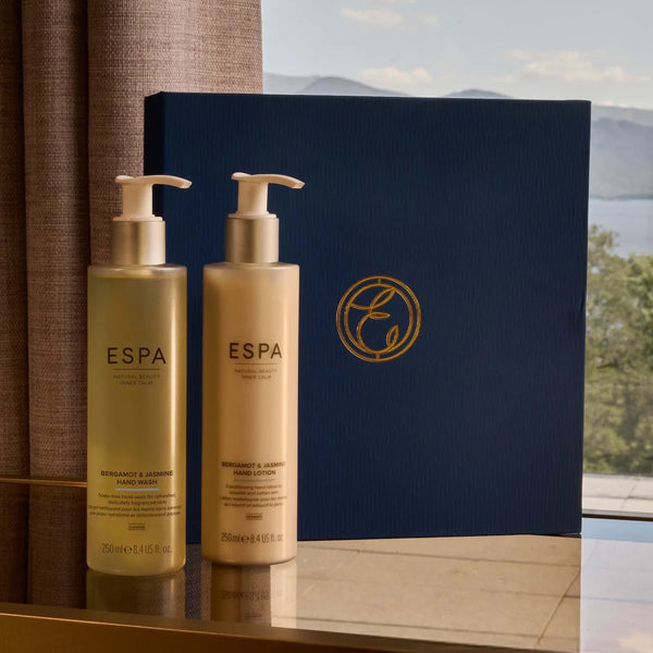 Two ESPA hand care products on a reflective surface with a scenic background