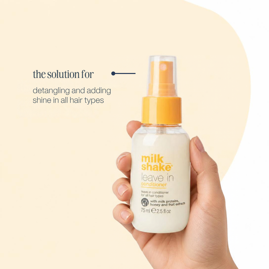A hand holding a bottle of Milk Shake Leave In Conditioner against a warm beige background with promotional text on the left.