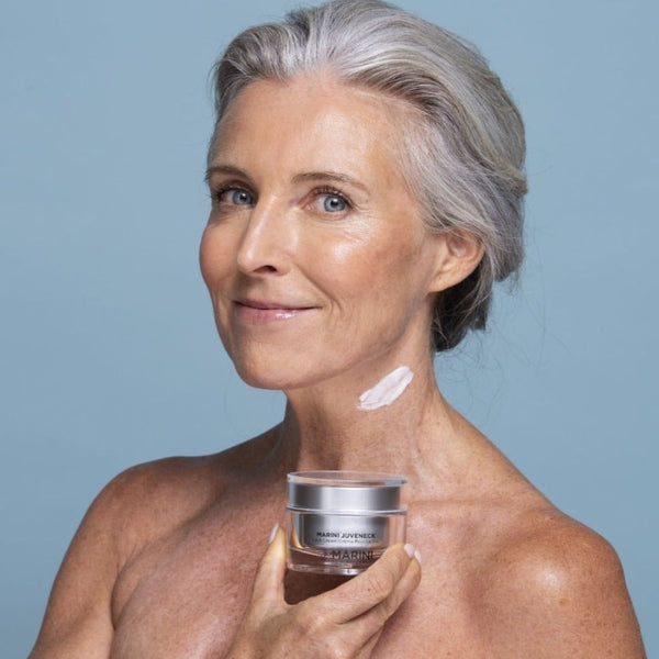 a model holding the cream to her neck with a smear of cream on her jaw