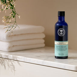Neal's Yard Remedies Aromatic Foaming Bath bottle next to a set of towels