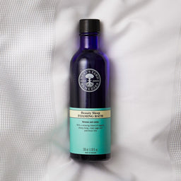 Neal's Yard Remedies Beauty Sleep Foaming Bath bottle on a bedsheet