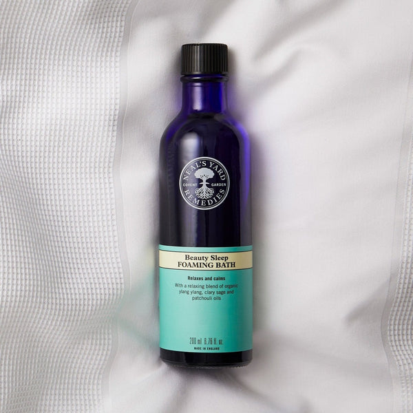 Neal's Yard Remedies Beauty Sleep Foaming Bath bottle on a bedsheet