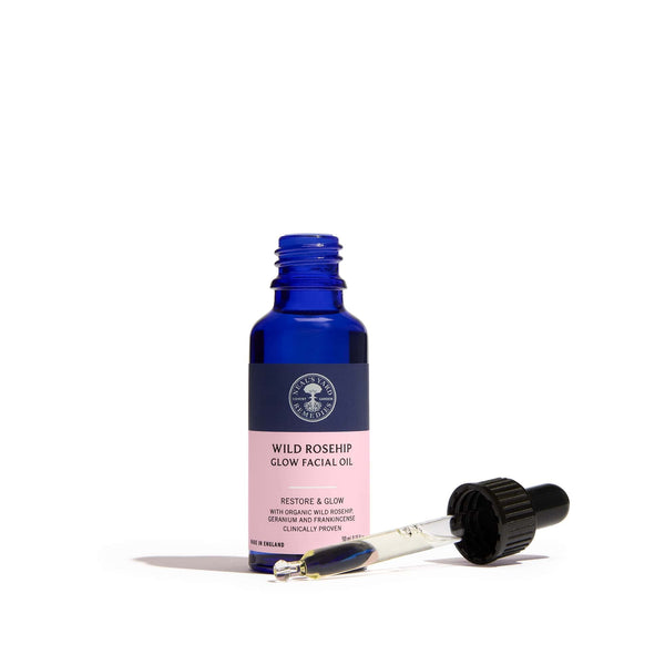 Blue facial oil bottle with pink label on a white background