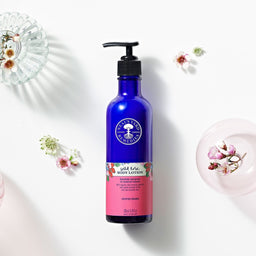 Neal's Yard Remedies Wild Rose Body Lotion bottle next to a range of small flowers