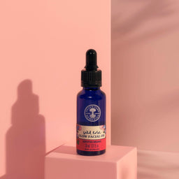 Neal's Yard Remedies Wild Rose Facial Oil on a pink background