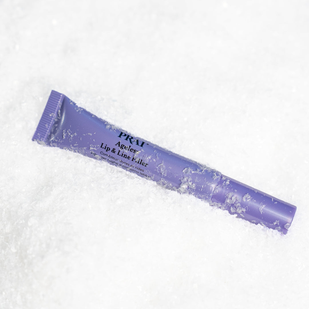 A purple squeeze tube of PRM Ageless Lip & Line T- liner placed diagonally on a bed of white snow.