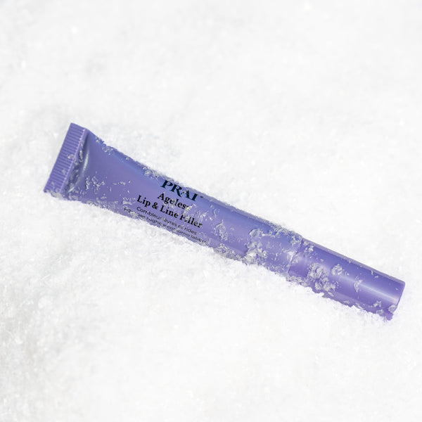A purple squeeze tube of PRM Ageless Lip & Line T- liner placed diagonally on a bed of white snow.