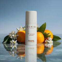 Oskia skincare product with oranges and flowers on a reflective surface