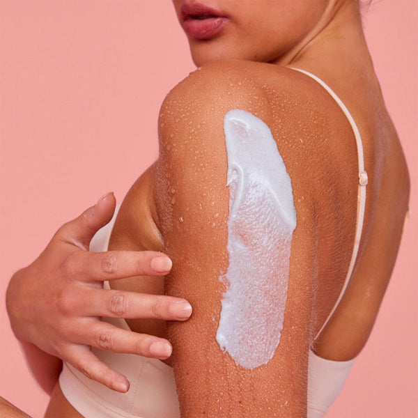 a closeup of a women applying the lotion to her arm